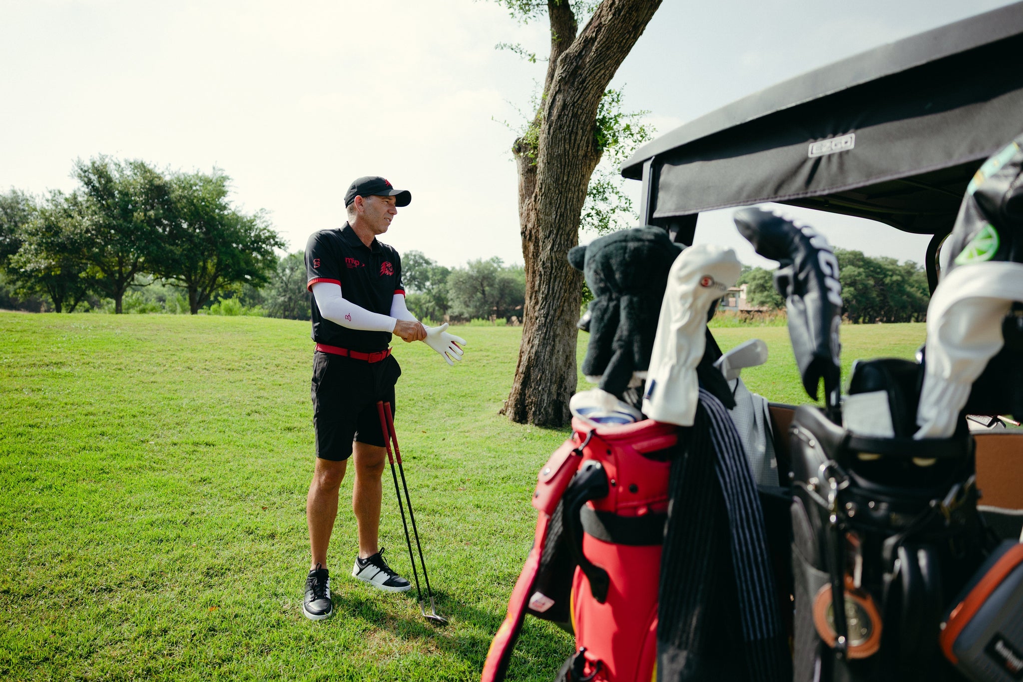 Golf player standing next to golf cart.