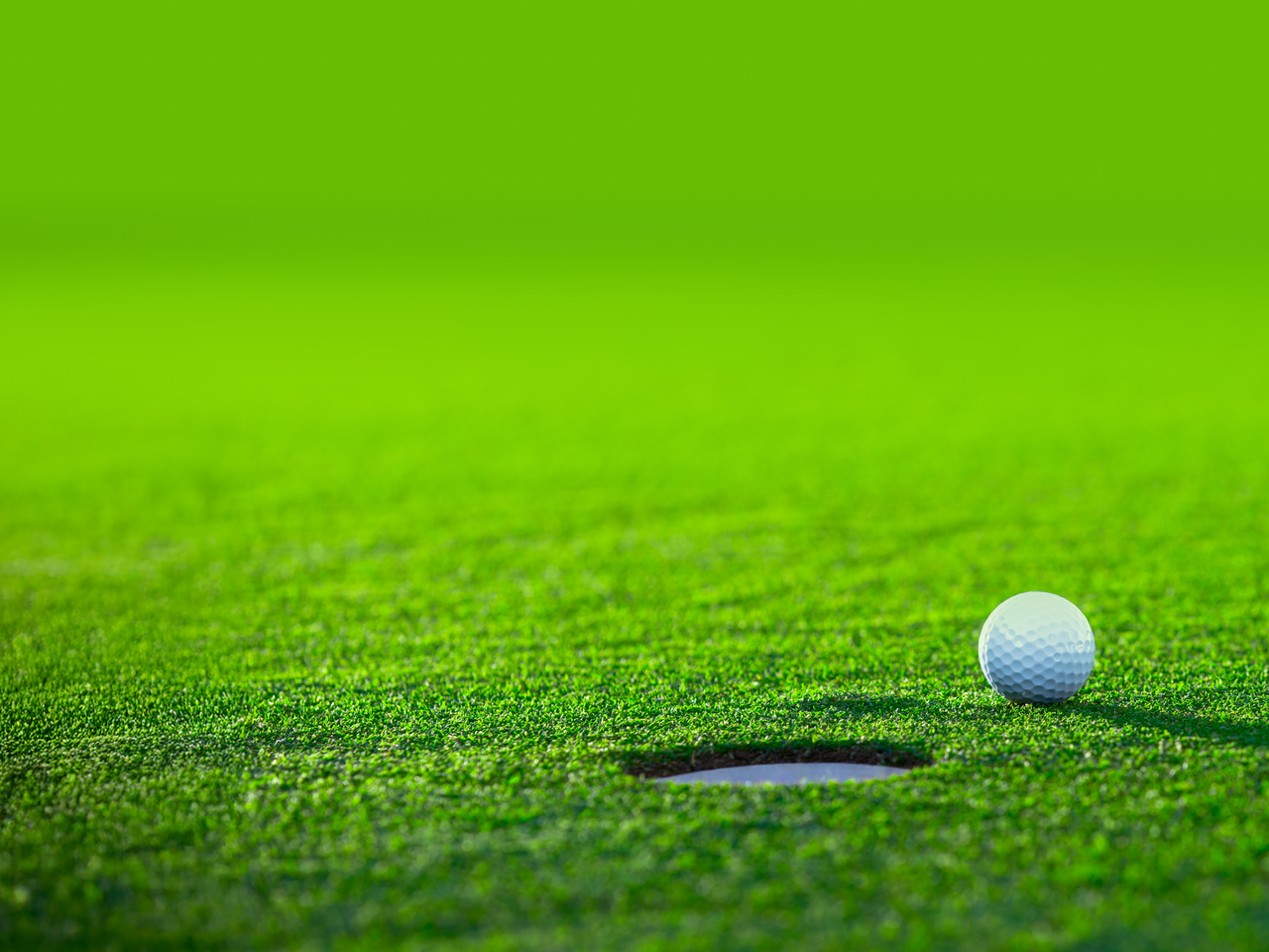 Golf ball sitting on putting green near hole