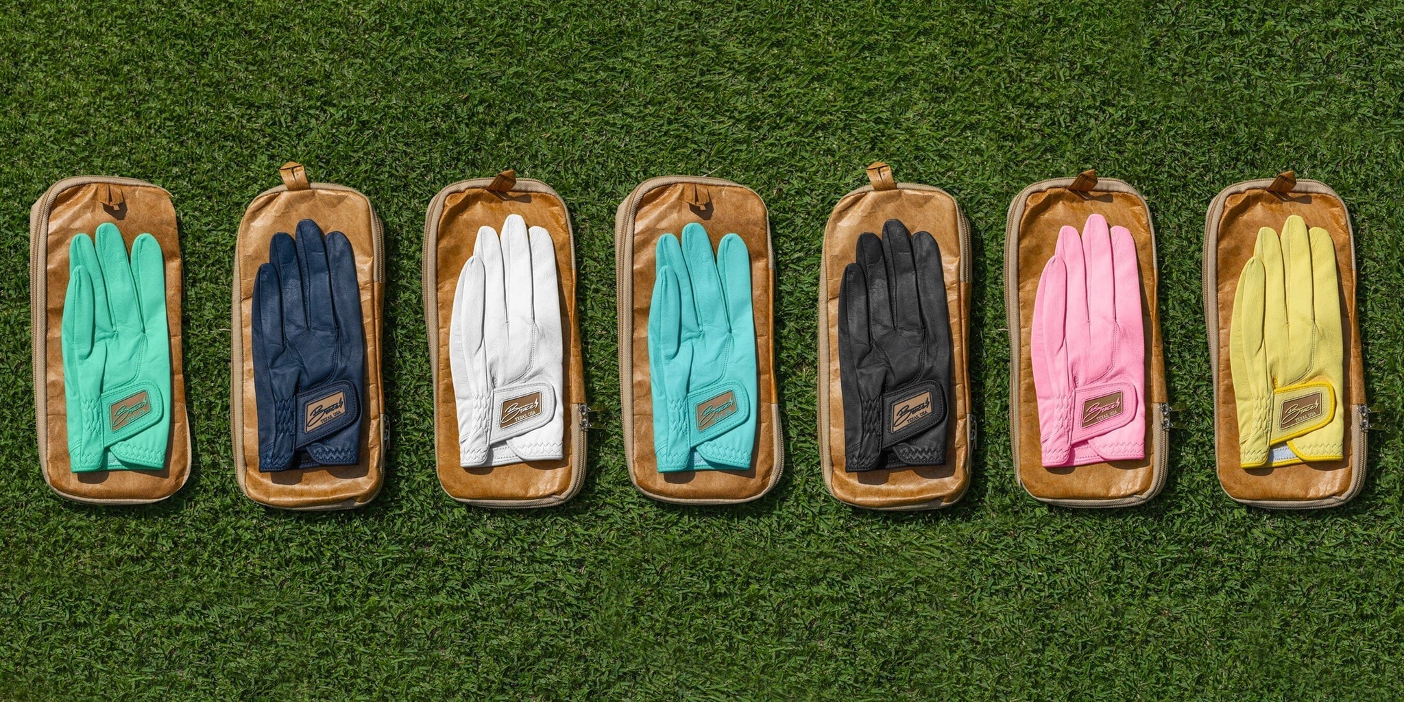 Several pairs of Bruce Bolt Golf Gloves laying on the grass.