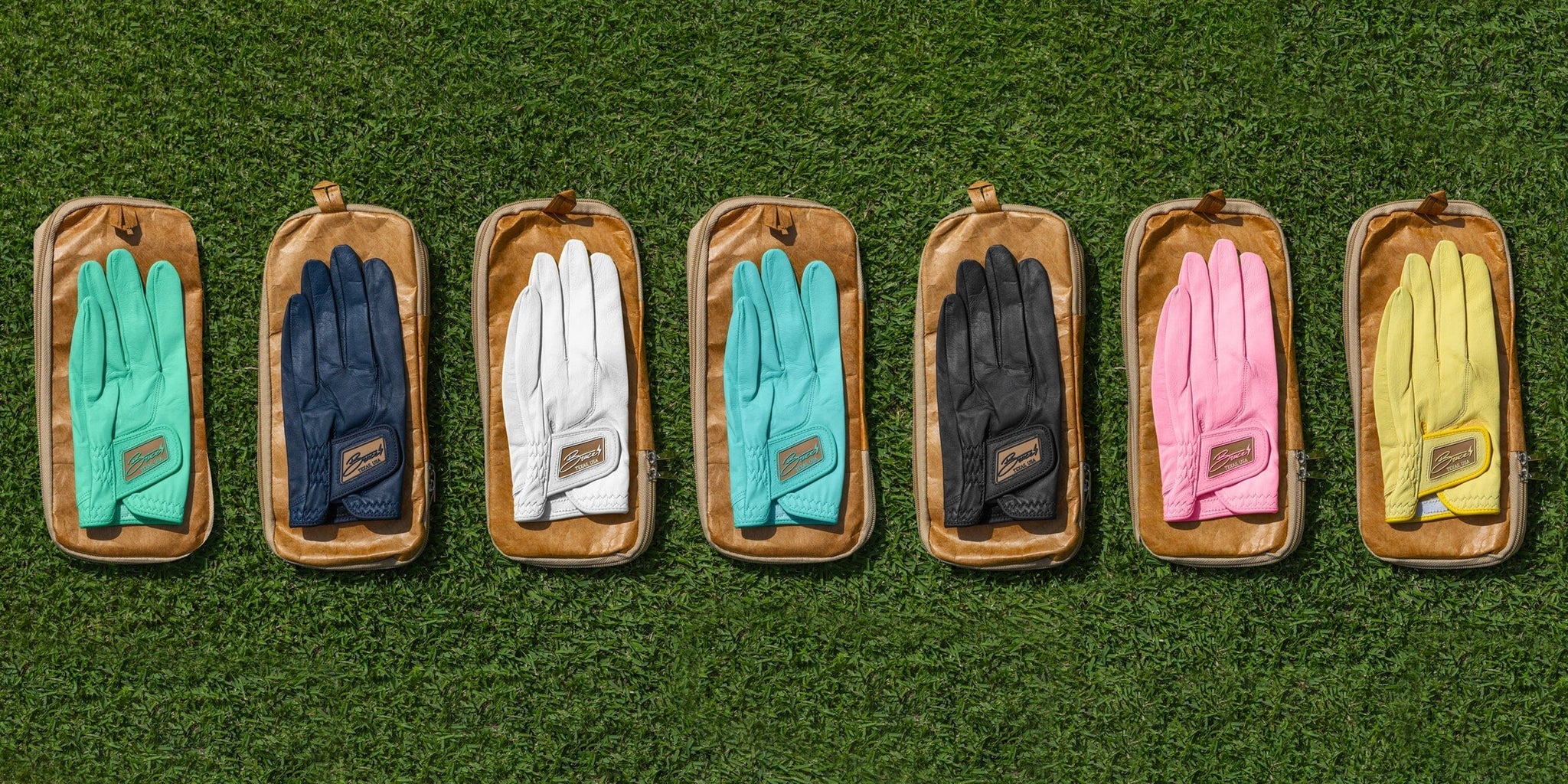 Several pairs of Bruce Bolt Golf Gloves laying on the grass.